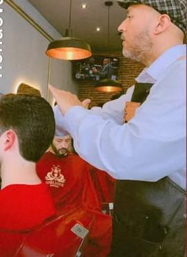 Barbero con boina atendiendo a un cliente